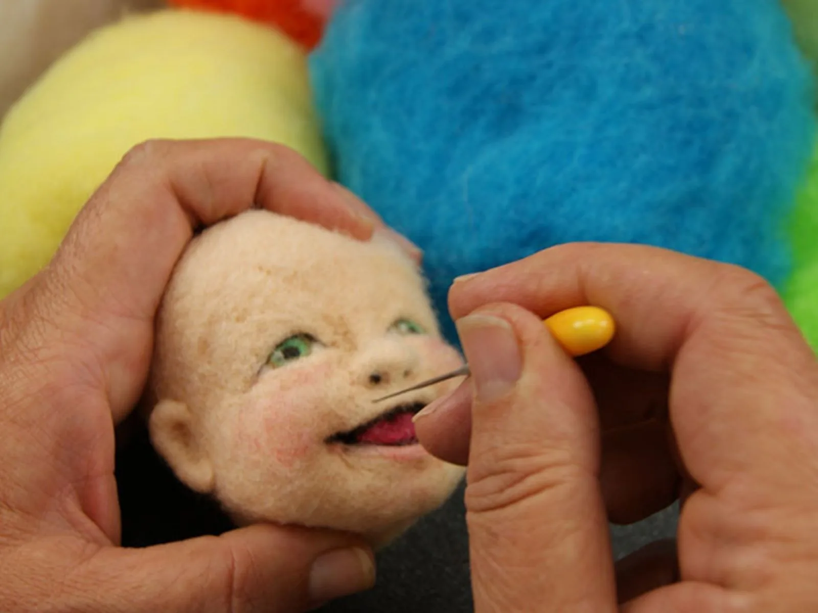 Kay Petal needle felting a wool doll face with a Felt Alive yellow comfort-grip felting needle
