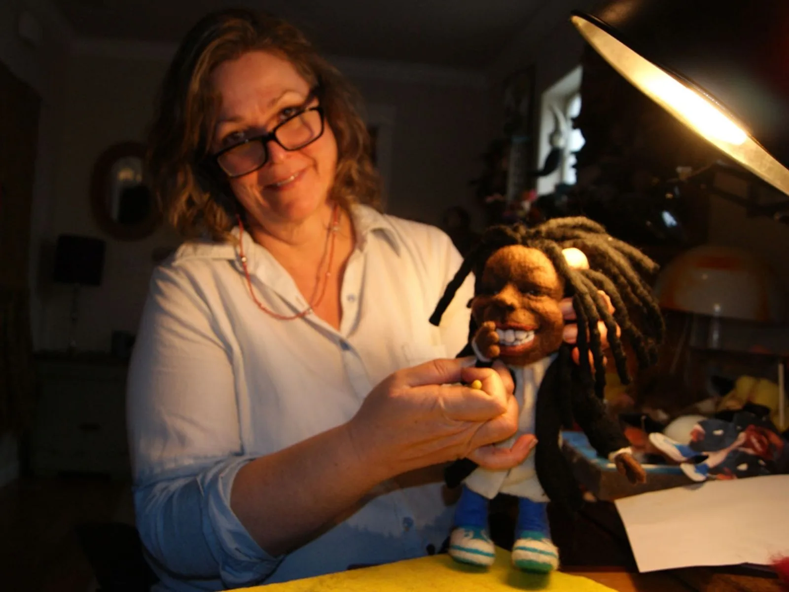 Kay Petal of Felt Alive in the studio with a needle-felted doll and a yellow comfort-grip needle
