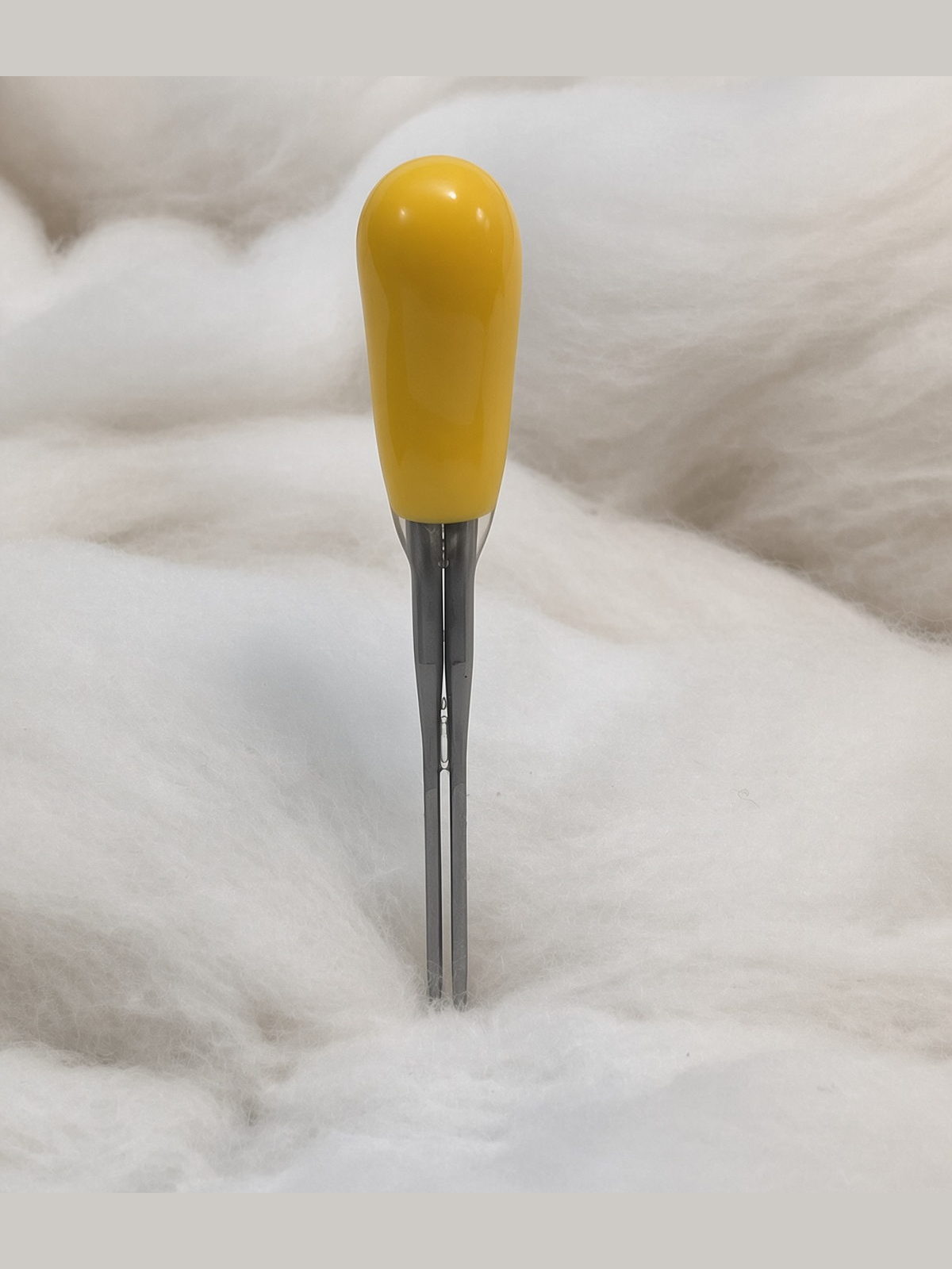 Felt Alive yellow double felting needle with two steel points and glossy teardrop handle on natural wool