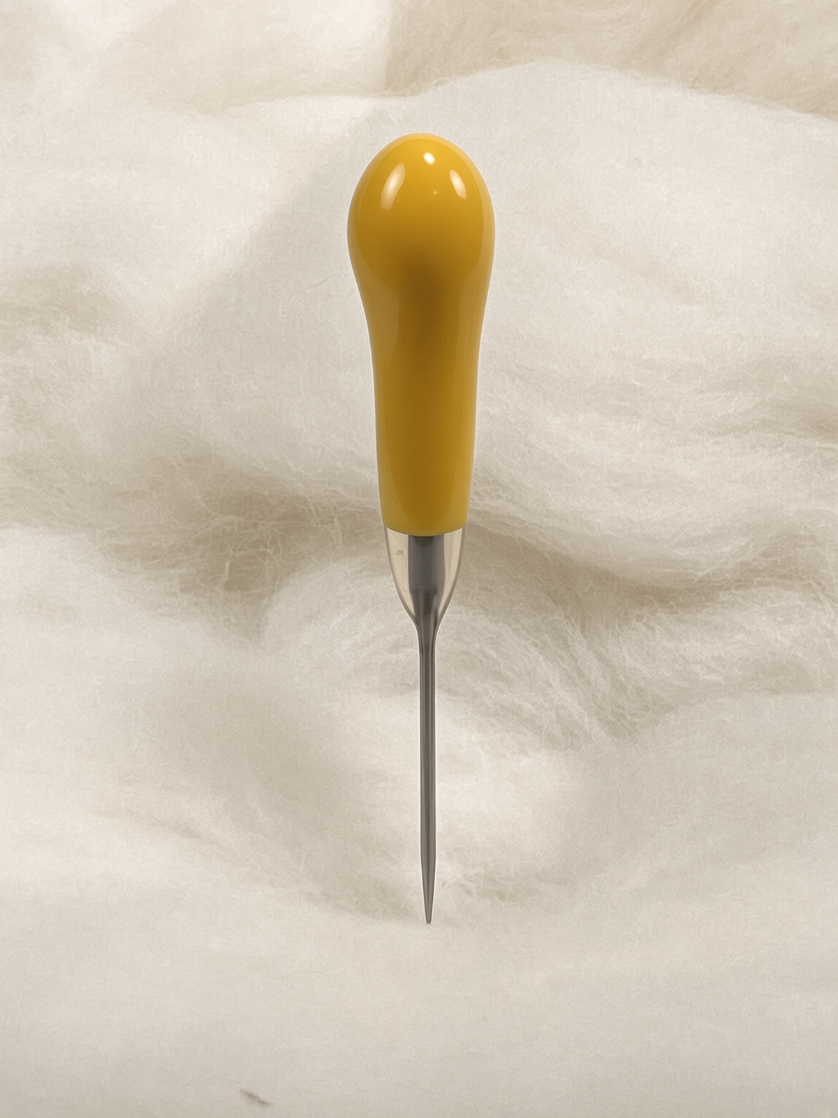 Felt Alive yellow single felting needle with glossy teardrop handle on wool